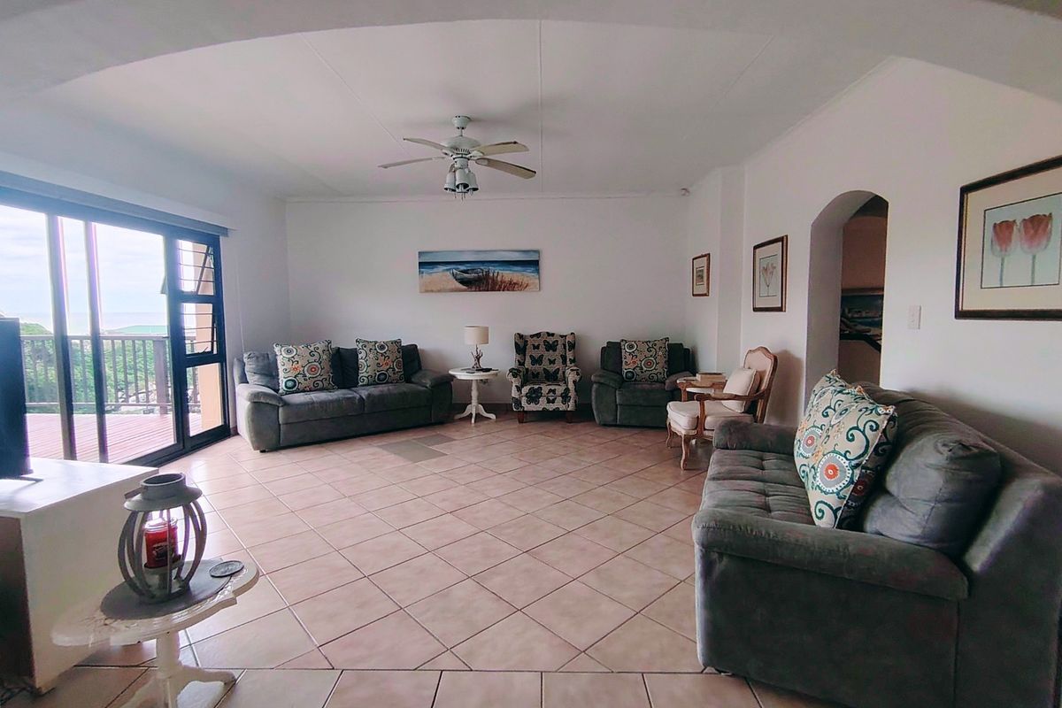 Spacious living room featuring tiled flooring, a ceiling fan, and large sliding glass doors providing access to an outdoor balcony area.