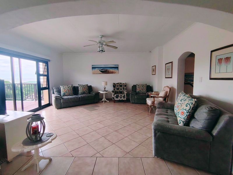 Spacious living room featuring tiled flooring, a ceiling fan, and large sliding glass doors providing access to an outdoor balcony area.
