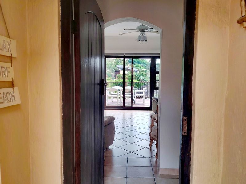 An arched entryway leading into an open-plan living area with tiled floors and sliding glass doors opening to a balcony.
