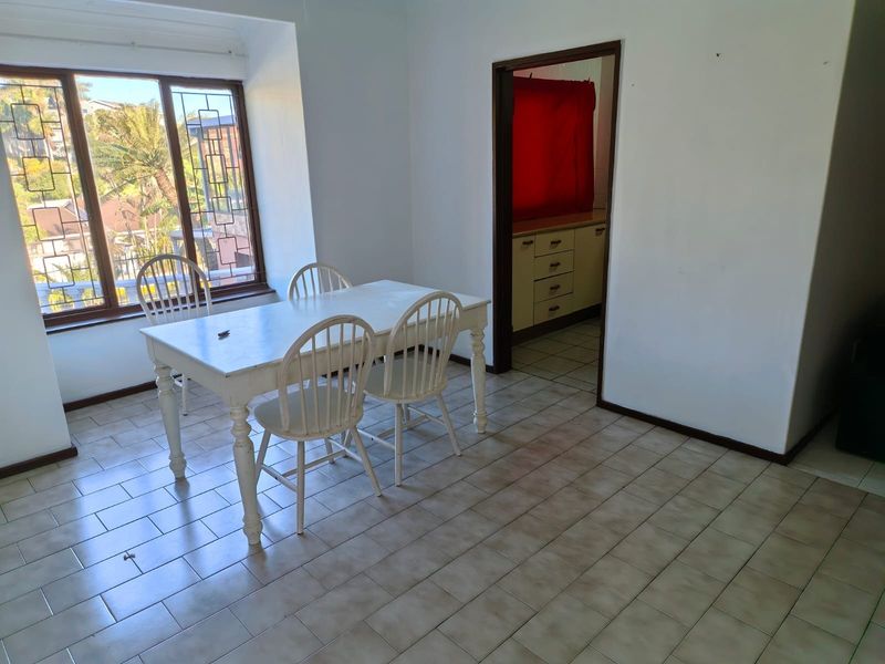 A dining area featuring tiled flooring and a leaded glass window, with an open doorway leading into the adjacent kitchen space.