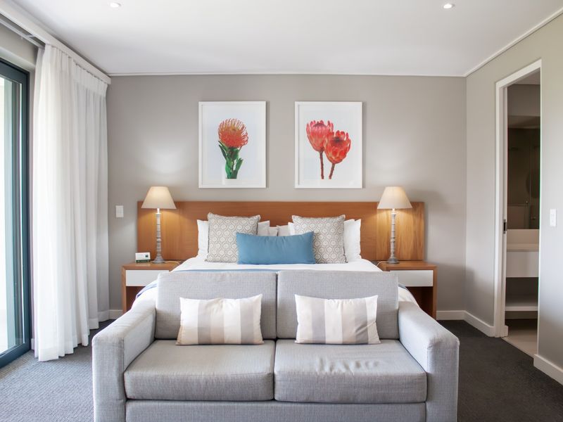 A well-maintained bedroom featuring a built-in wooden headboard, recessed lighting, and direct access to a balcony through sliding glass doors.
