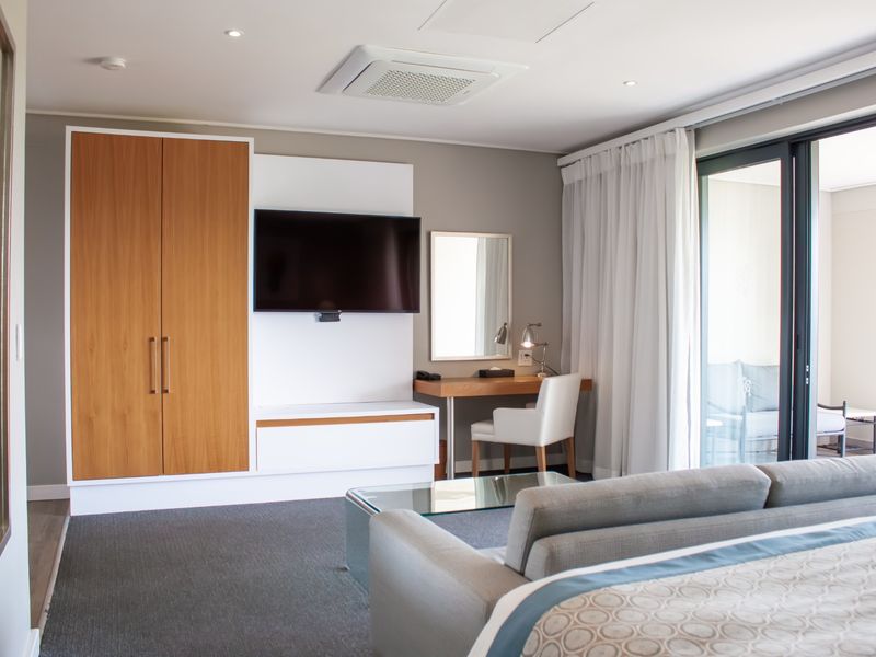 A modern, well-maintained bedroom featuring built-in cabinetry, recessed lighting, integrated air conditioning, and direct access to a private balcony through sliding glass doors.