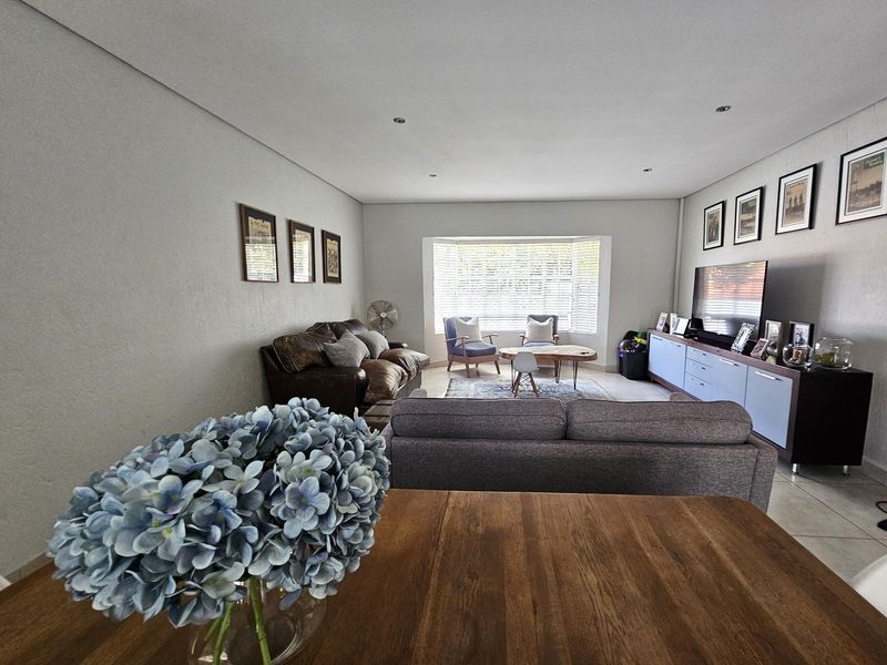 Spacious open-plan living area featuring tiled flooring, recessed downlights, and a large bay window that provides ample natural light.