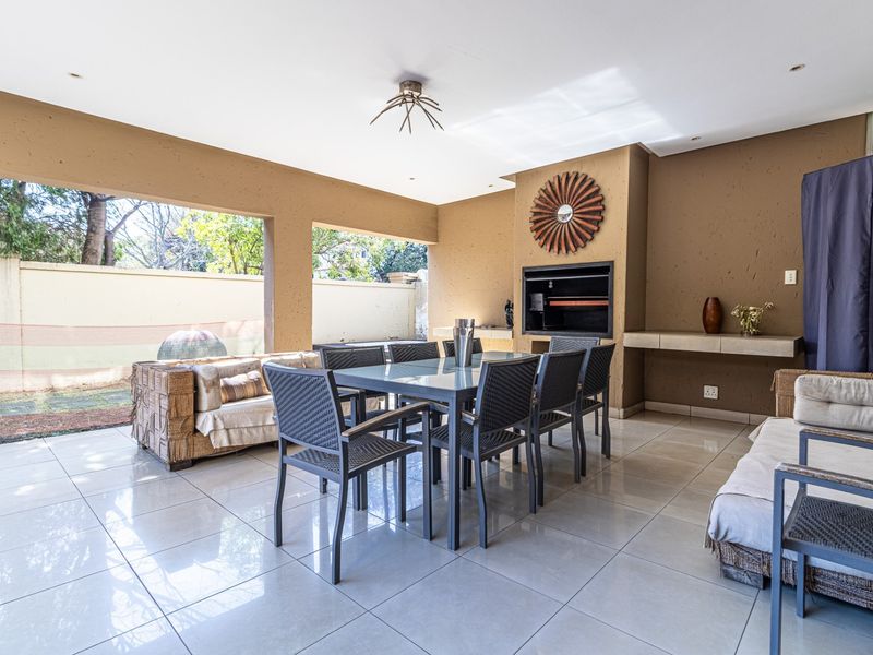 Spacious covered patio featuring a built-in braai, tiled flooring, and recessed lighting, perfect for outdoor entertaining and dining.