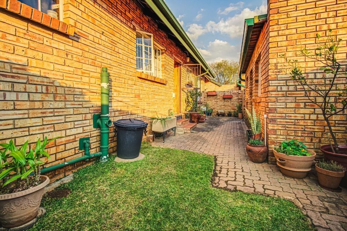 A side exterior view of the property featuring face brick walls, a paved walkway, and a small lawn area.