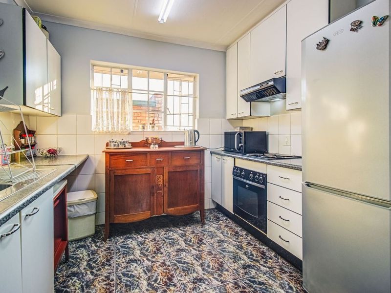 Functional kitchen featuring white cabinetry, tiled backsplash, built-in oven with extractor fan, and patterned tiled flooring.