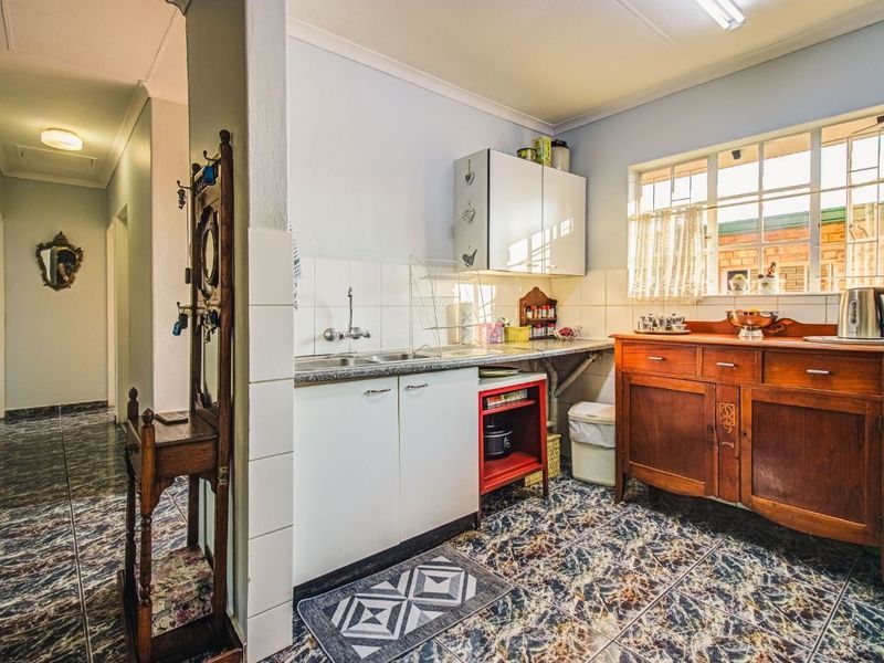 A functional scullery area featuring a stainless steel sink, tiled splashback, and built-in cabinetry, providing additional prep and storage space.