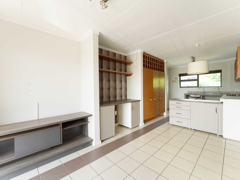 Open plan living and kitchen area featuring tiled flooring, built-in cabinetry, a dedicated workspace, and functional kitchen fixtures.