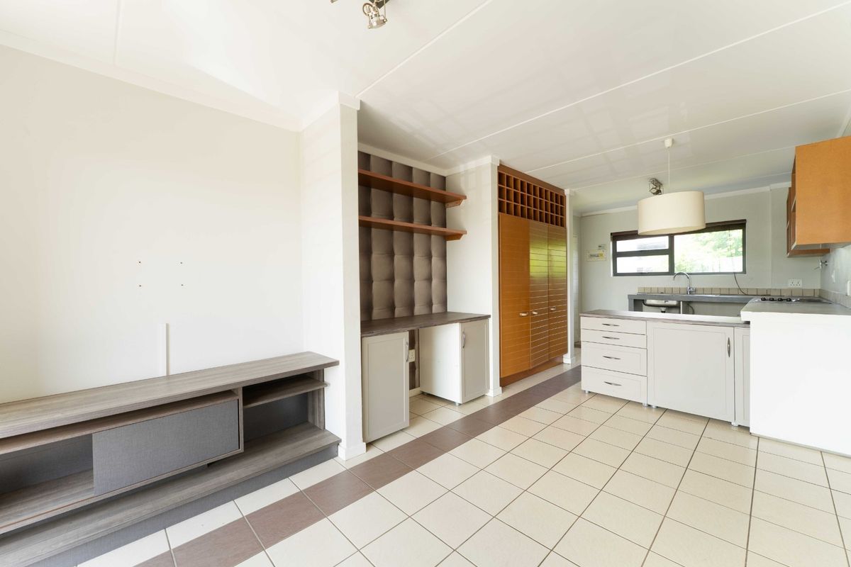 Open plan living and kitchen area featuring tiled flooring, built-in cabinetry, a dedicated workspace, and functional kitchen fixtures.