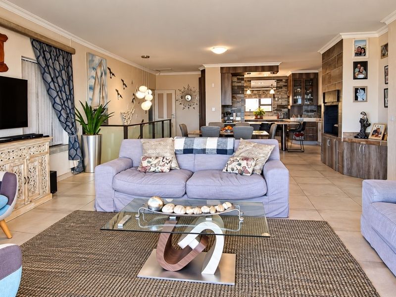 Spacious open-plan living and dining area featuring tiled floors, a modern kitchen with island, and a stone feature wall, creating a cohesive living space.