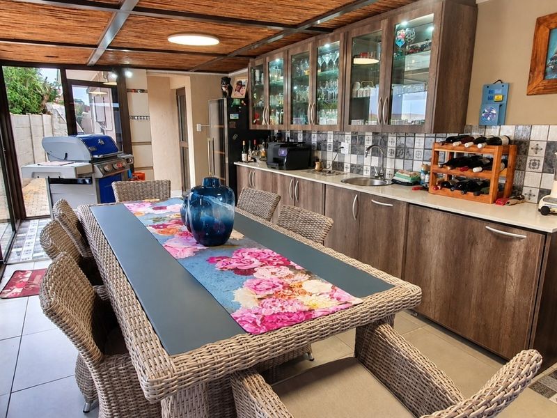 Covered patio area featuring built-in cabinetry, sink, and tiled backsplash, providing a functional space for outdoor dining and entertainment.
