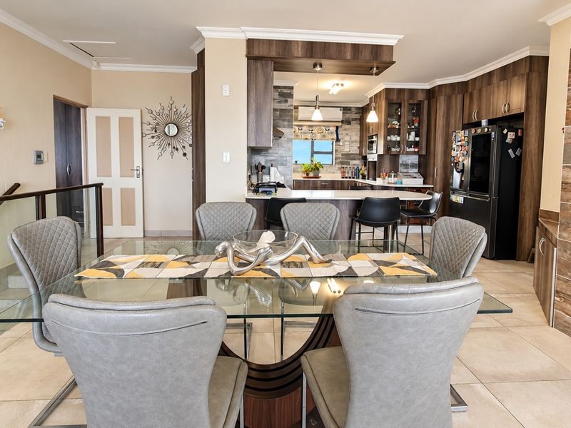 Spacious open-plan living and dining area featuring a modern kitchen with stone countertops, breakfast bar, and a built-in fireplace with stone cladding.