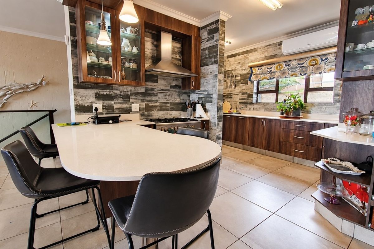 A well-appointed kitchen featuring dark wood cabinetry, stone countertops, a gas stove with stainless steel extractor, and tiled flooring throughout.