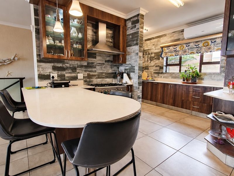 A well-appointed kitchen featuring dark wood cabinetry, stone countertops, a gas stove with stainless steel extractor, and tiled flooring throughout.