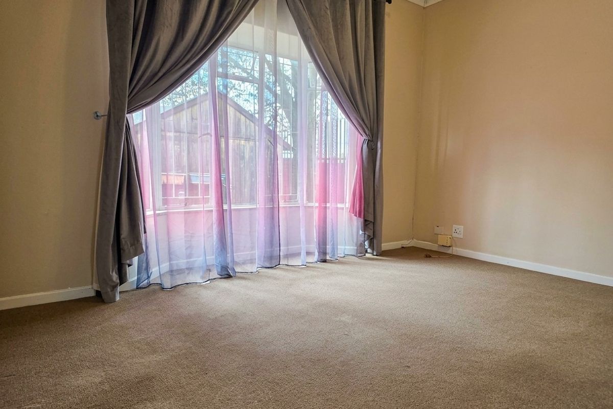 A vacant bedroom featuring carpeted flooring and a large bay window, providing a neutral canvas for personalization.