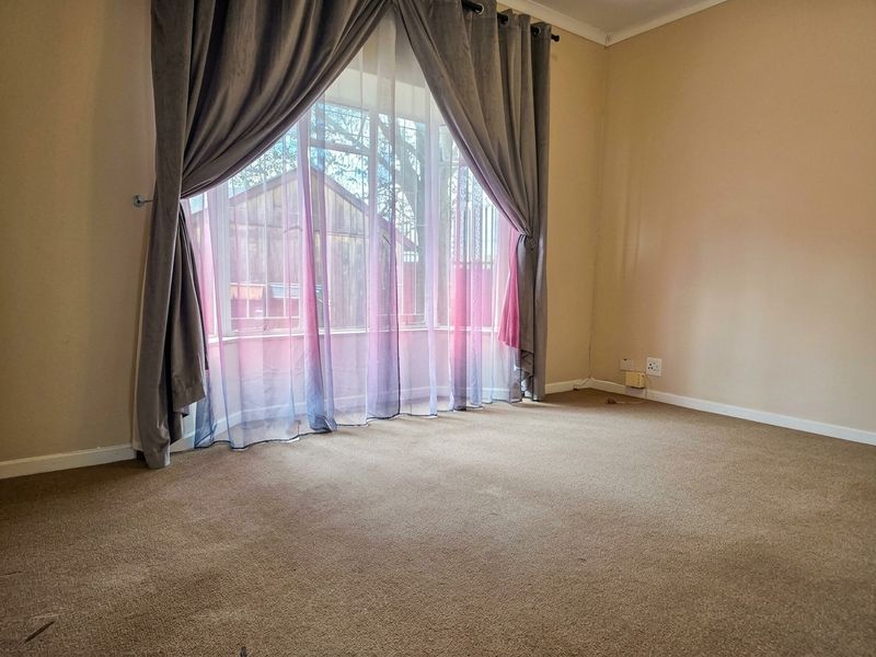 A vacant bedroom featuring carpeted flooring and a large bay window, providing a neutral canvas for personalization.