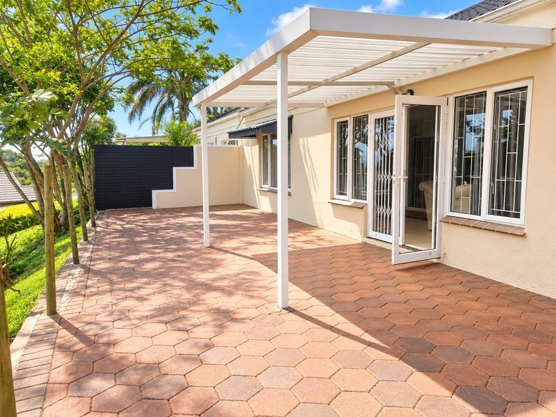 A well-maintained paved patio area featuring a modern white pergola, providing a clean and inviting outdoor space for relaxation.