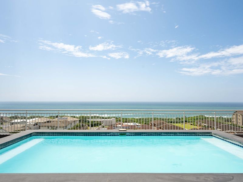 A pristine elevated swimming pool featuring a modern metal balustrade and expansive, unobstructed ocean views.