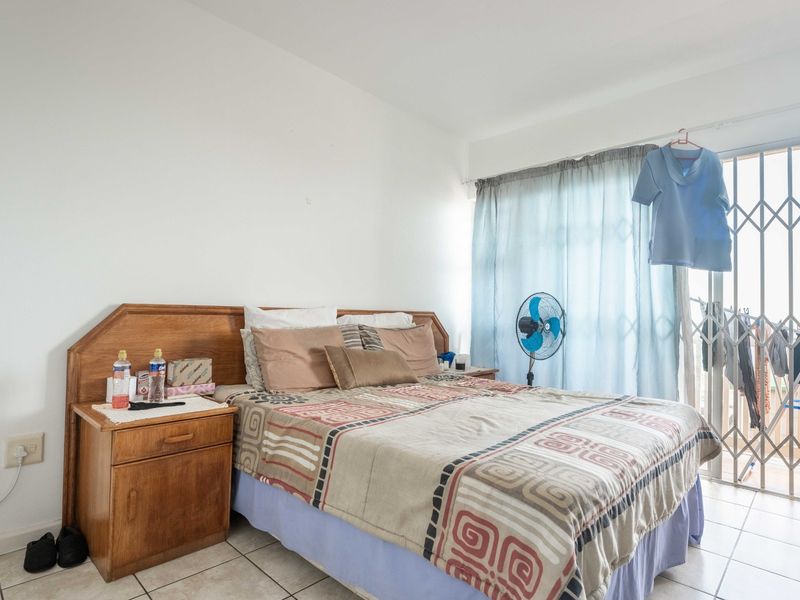 A bedroom featuring tiled flooring and a sliding glass door with a security gate, providing access to an outdoor area.