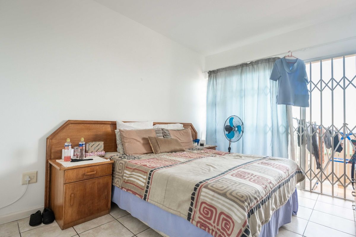 A bedroom featuring tiled flooring and a sliding glass door with a security gate, providing access to an outdoor area.