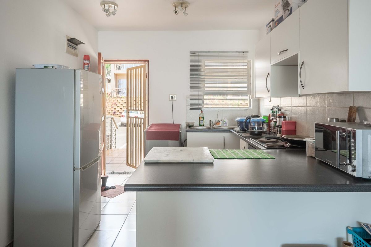 Functional kitchen featuring built-in cabinetry, laminate countertops, a stainless steel sink, and a hob, with direct access to an exterior entrance.