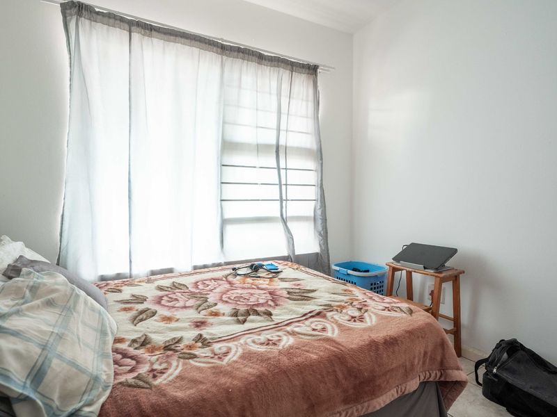 A standard bedroom featuring a large window with installed curtain rails and neutral wall finishes.