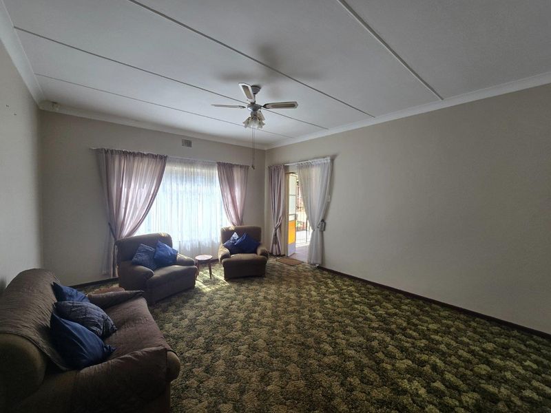 Spacious living room featuring a ceiling fan, large windows for natural light, and direct access to an outdoor area.