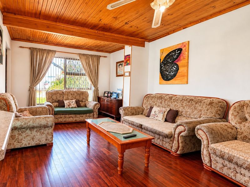 A comfortable living room featuring warm timber ceilings, laminate flooring, and a ceiling fan, providing a cozy and inviting atmosphere.