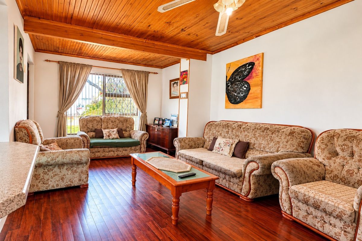 A comfortable living room featuring warm timber ceilings, laminate flooring, and a ceiling fan, providing a cozy and inviting atmosphere.