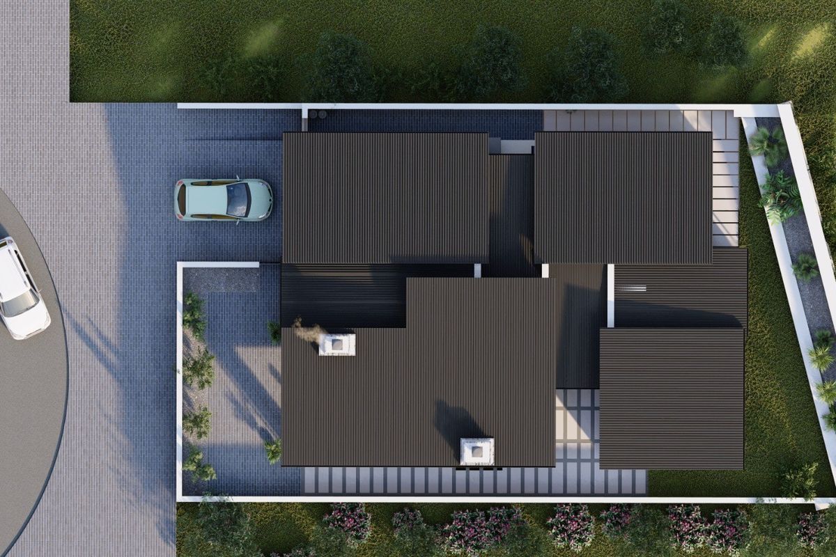 An aerial view of a residential property featuring a modern corrugated metal roof, paved driveway, and perimeter boundary wall.