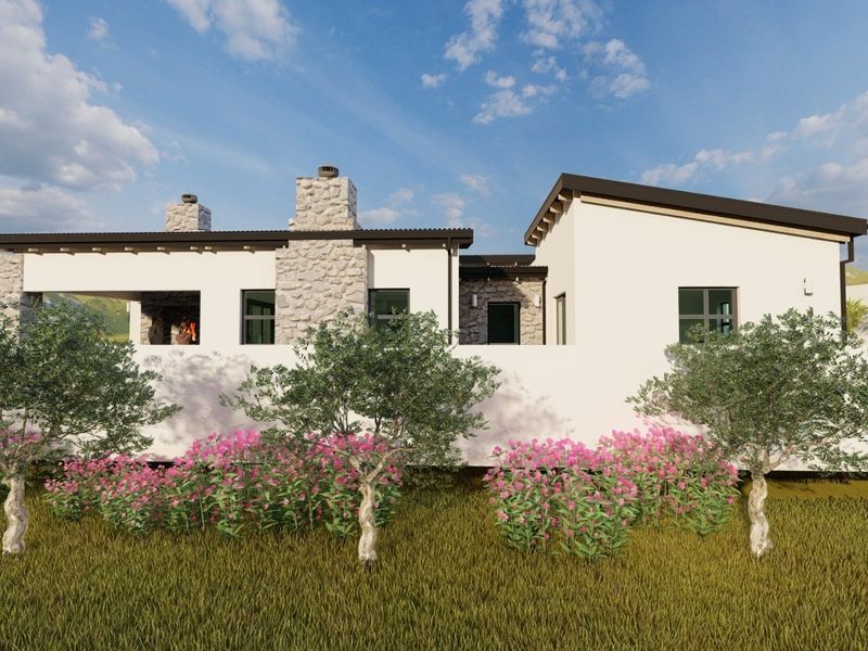 A rear view of a modern residential property featuring stone chimneys, a covered patio area, and a clean stucco finish.