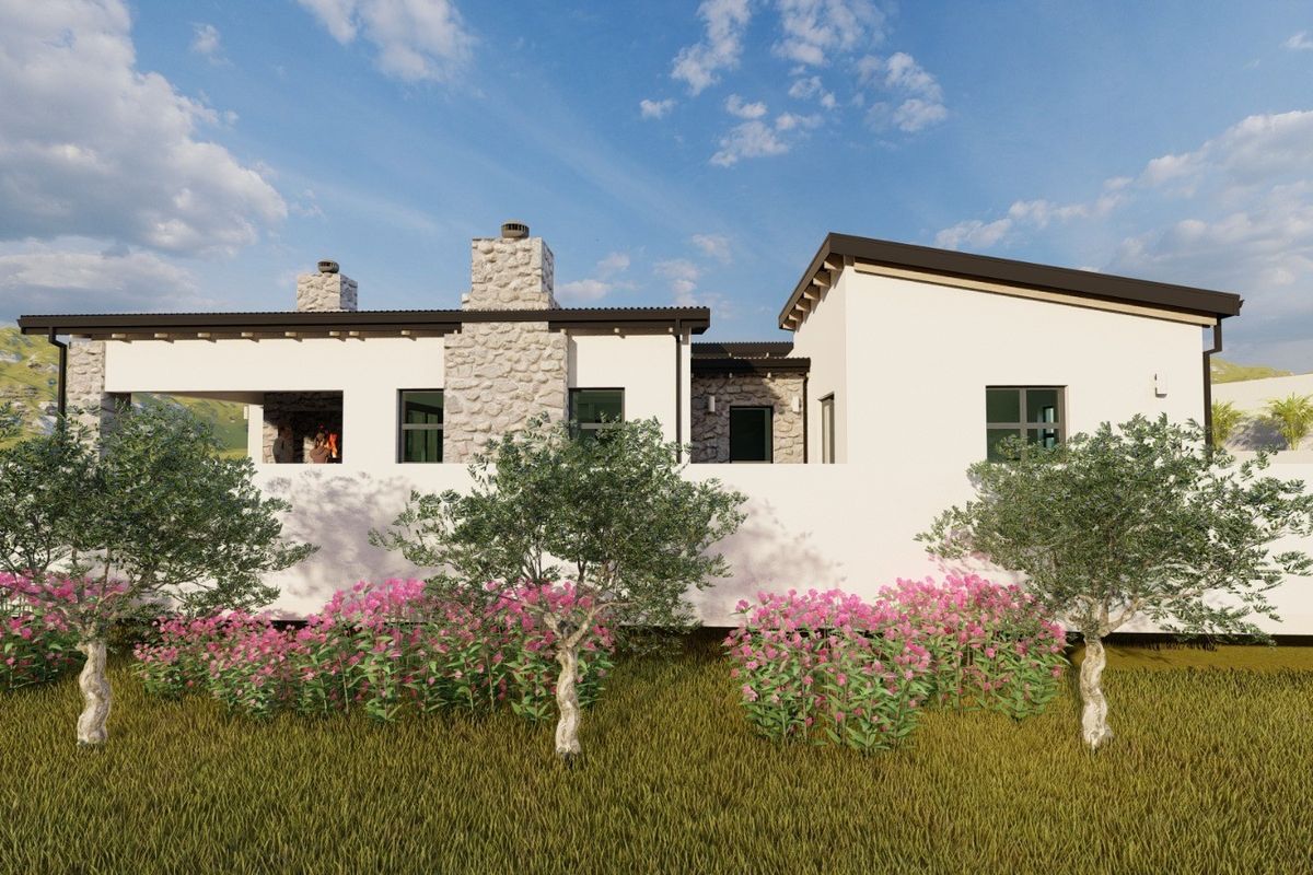 A rear view of a modern residential property featuring stone chimneys, a covered patio area, and a clean stucco finish.