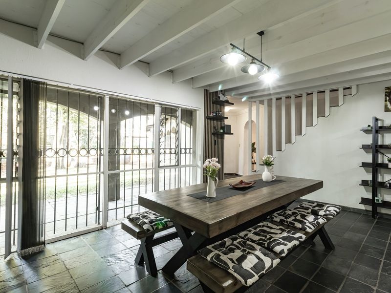 Dining area featuring slate tile flooring, exposed beam ceiling, and large sliding glass doors providing access to the outdoor patio.