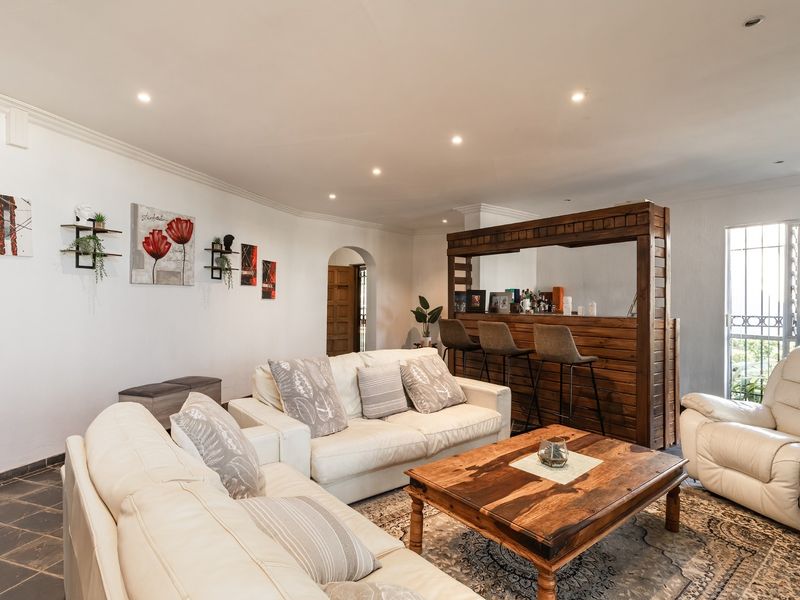 Spacious living room featuring tiled flooring, recessed downlights, and a built-in wooden bar area, creating a comfortable and functional entertainment space.