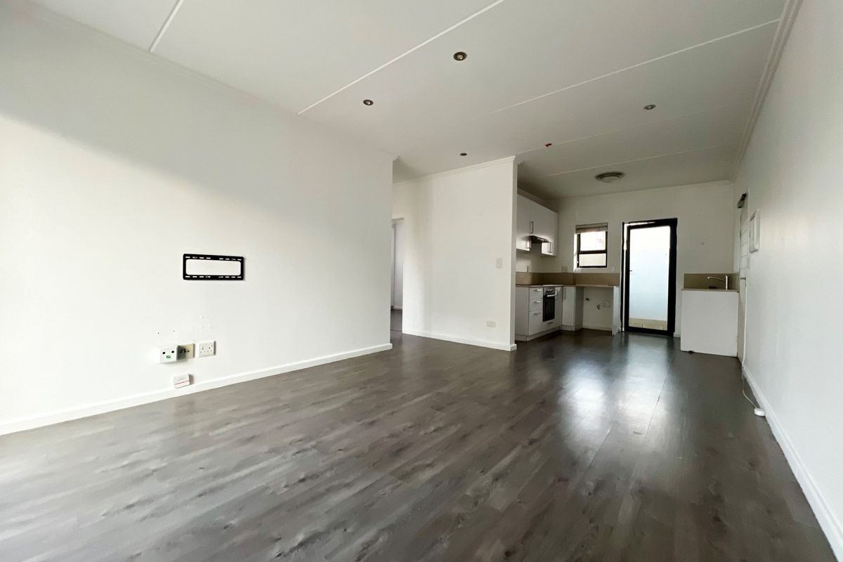 Spacious open-plan living area featuring modern laminate flooring, recessed lighting, and a functional kitchen with built-in cabinetry and appliances.