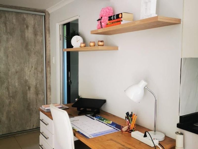 A functional home office space featuring built-in shelving, tiled flooring, and a sliding door, providing a compact and organized work area.