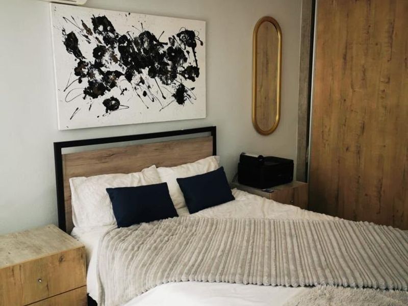 A well-maintained bedroom featuring a built-in wardrobe, tiled flooring, and a wall-mounted split-system air conditioner for climate control.