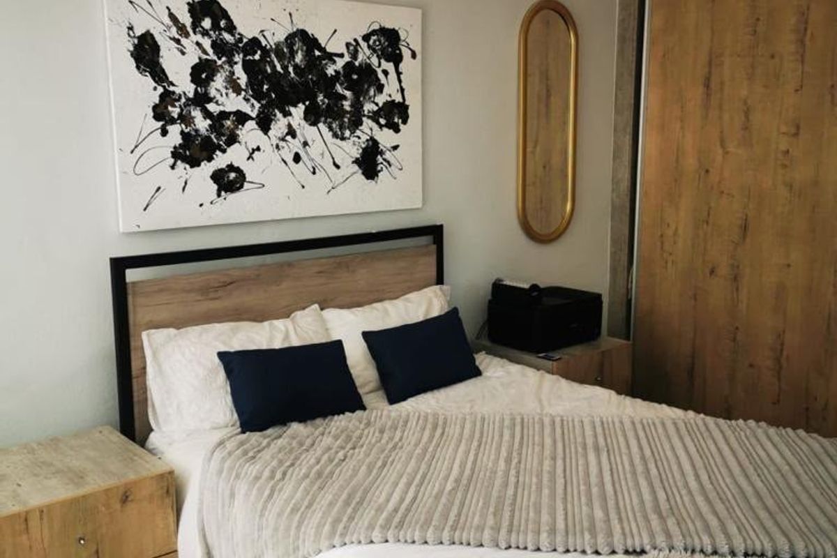 A well-maintained bedroom featuring a built-in wardrobe, tiled flooring, and a wall-mounted split-system air conditioner for climate control.