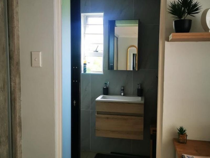 A modern bathroom featuring a wall-mounted vanity with basin, sleek tiled walls, and a sliding door entrance.
