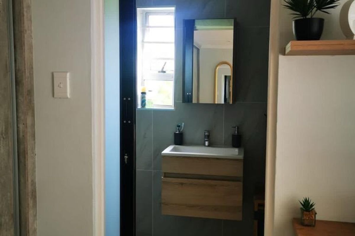 A modern bathroom featuring a wall-mounted vanity with basin, sleek tiled walls, and a sliding door entrance.