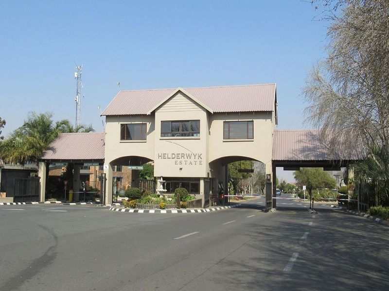The main entrance gatehouse of Helderwyk Estate, featuring a secure access point with boom gates and a structured architectural facade.