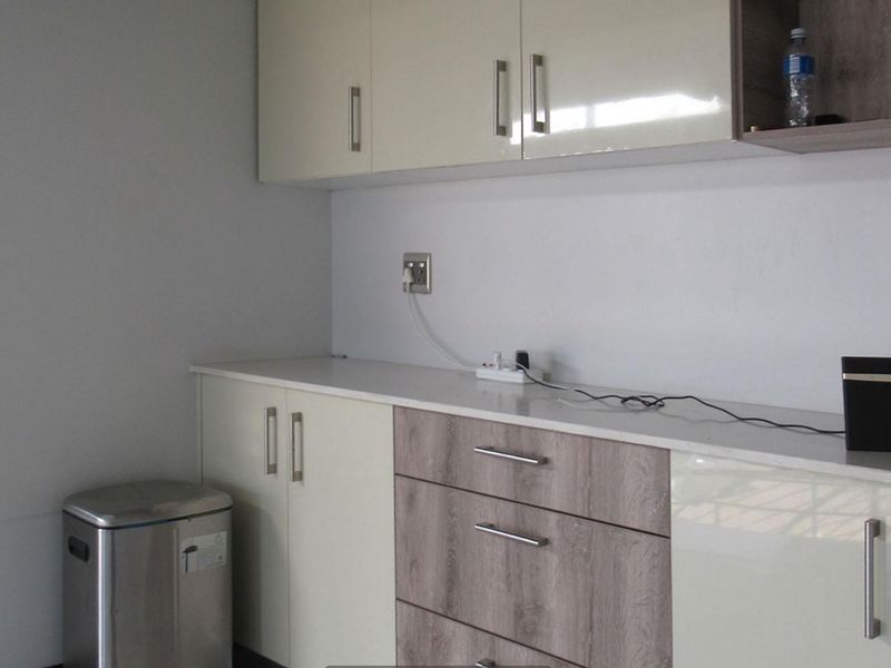 A clean, modern kitchen area featuring neutral-toned built-in cabinetry and ample countertop space, providing a functional and well-maintained prep area.