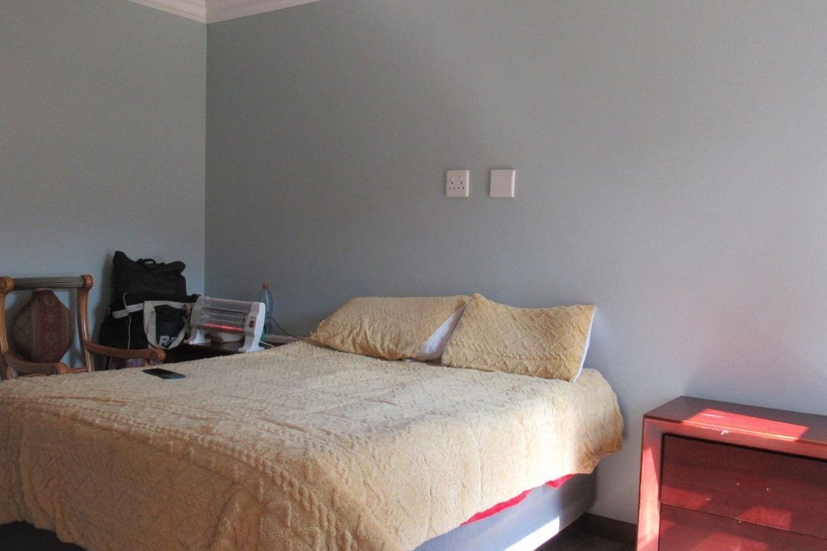 A simple bedroom featuring neutral wall paint, electrical outlets, and a light switch, providing a functional space for rest.