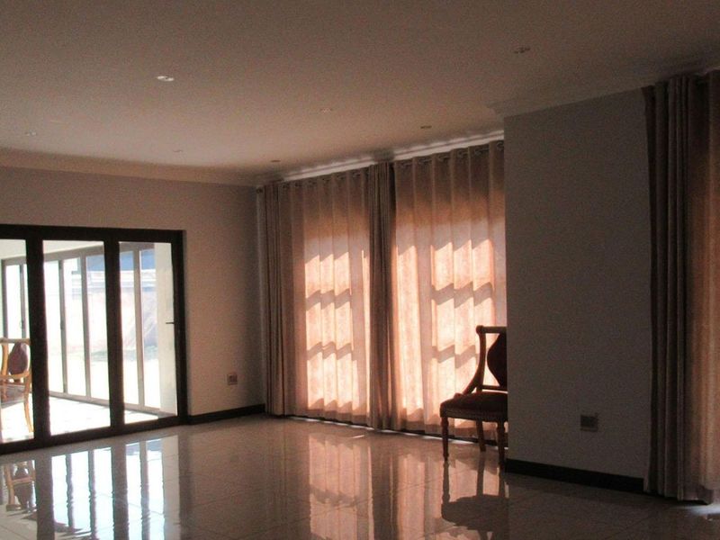 Spacious living area featuring polished tiled flooring, recessed downlighting, and large sliding glass doors providing access to the outdoor area.