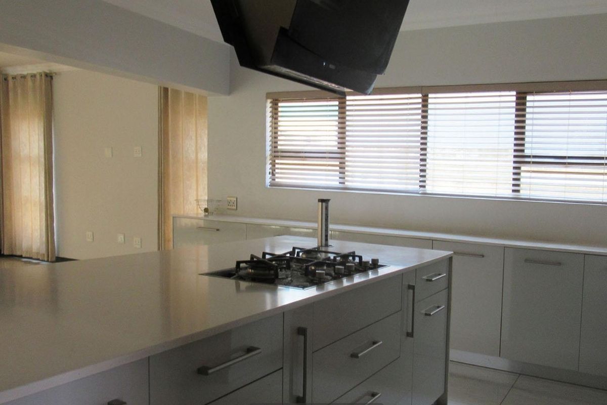 Modern kitchen featuring a central island with a built-in gas hob, extractor fan, and ample cabinetry, finished with clean lines and neutral tones.