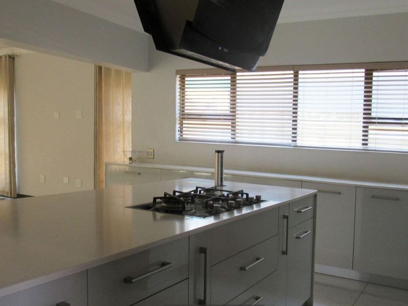Modern kitchen featuring a central island with a built-in gas hob, extractor fan, and ample cabinetry, finished with clean lines and neutral tones.