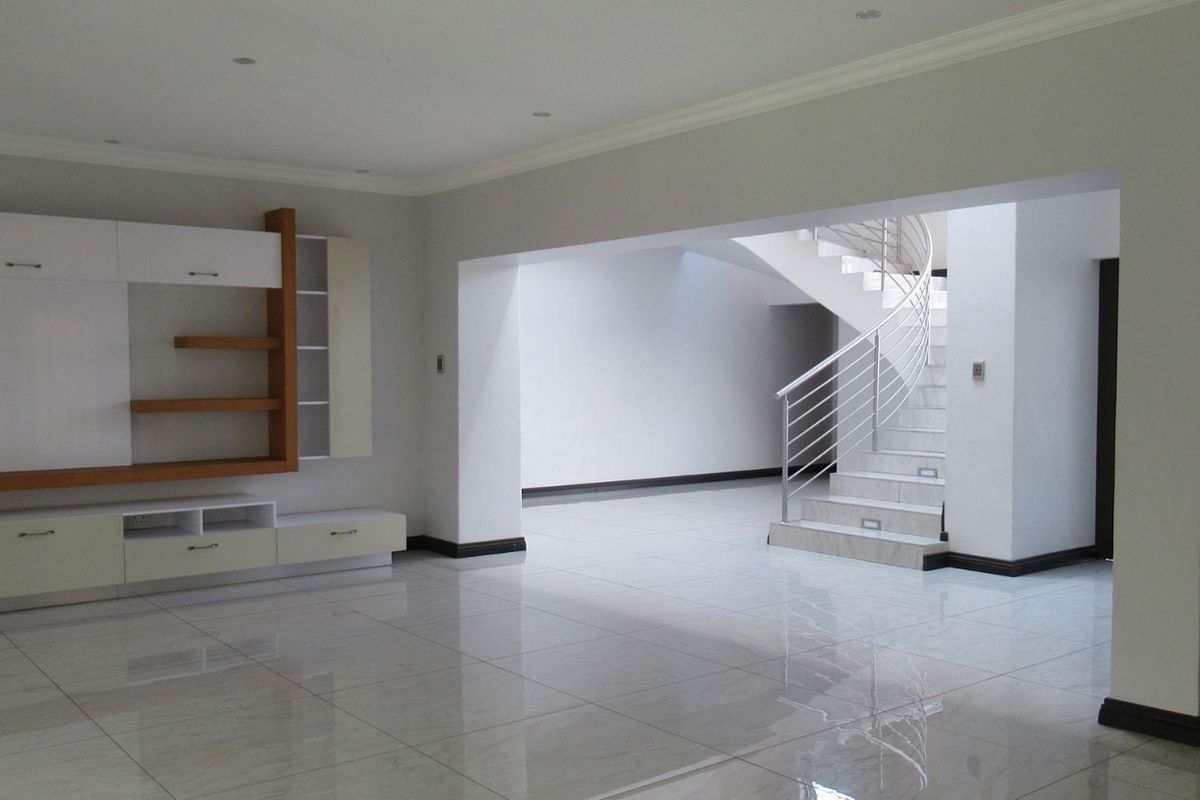Spacious open-plan living area featuring polished tiled floors, built-in cabinetry, and a modern spiral staircase with a metal balustrade.