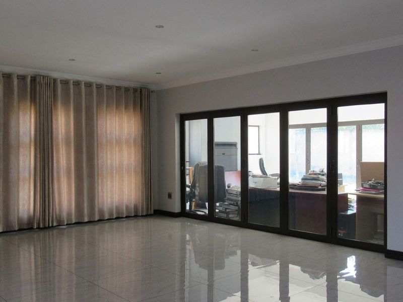 Spacious living area featuring polished tiled flooring, recessed downlights, and large sliding glass doors that provide ample natural light and access to an adjacent room.