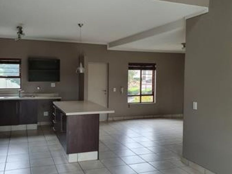 Spacious open-plan living and kitchen area featuring a central island, double-height ceilings, and a mezzanine level with a modern metal balustrade.
