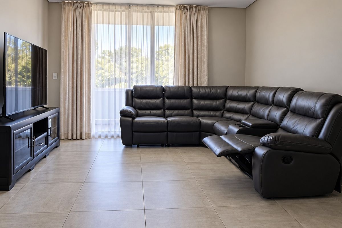 A well-maintained living room featuring neutral tiled flooring and a large sliding glass door that provides access to an outdoor area.